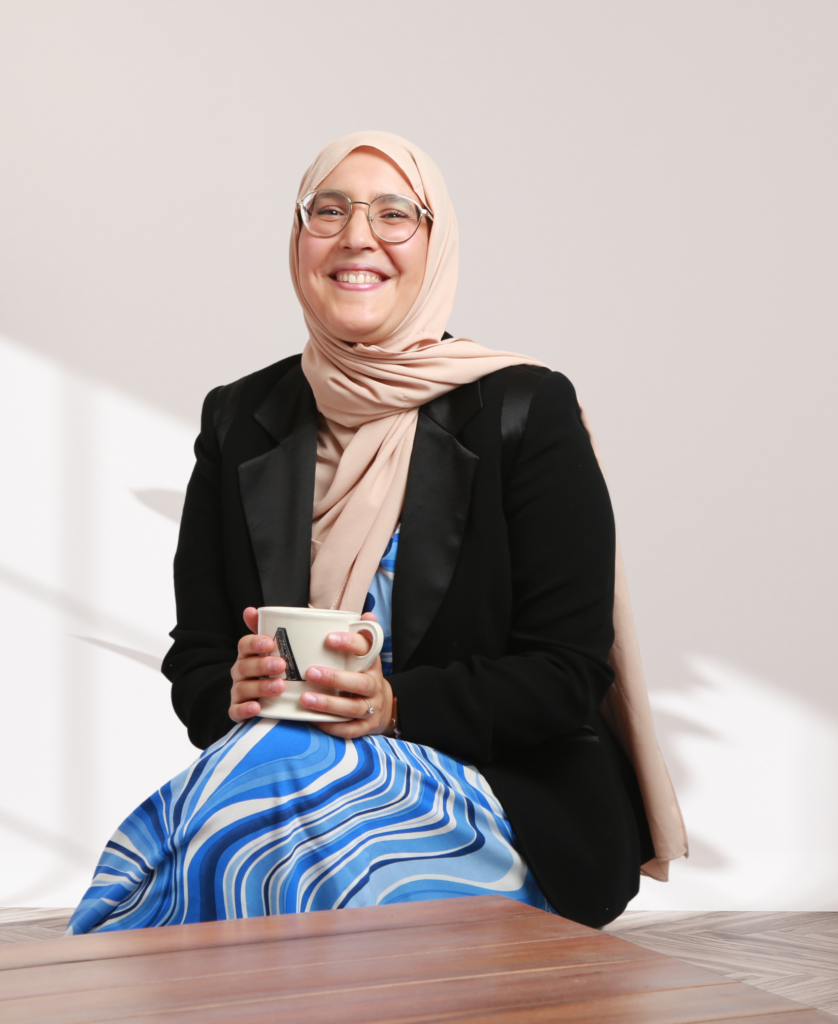 Amina, femme avec hijab rose, souriante, sa tasse dans les mains